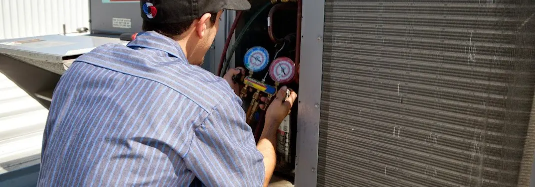 HVAC technician servicing a condenser unit in Gladstone